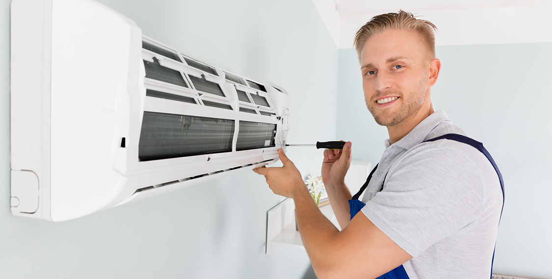 Smiling man working on an HVAC unit