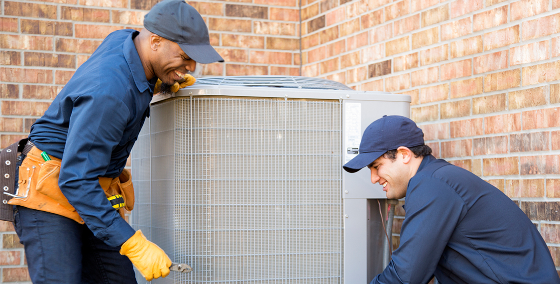 Two men working with an HVAC system