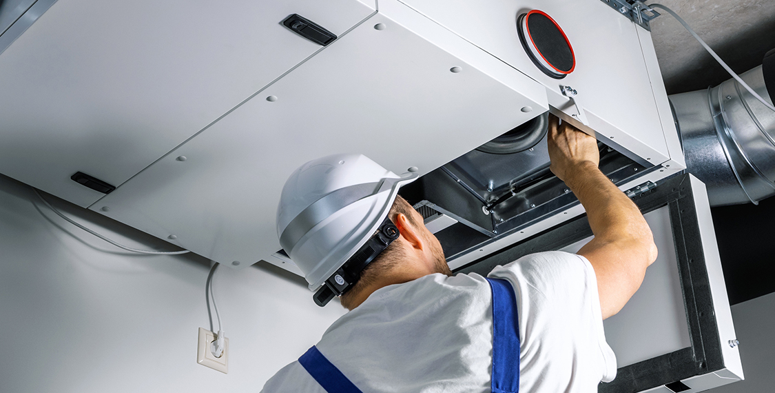 Man looking into an air duct