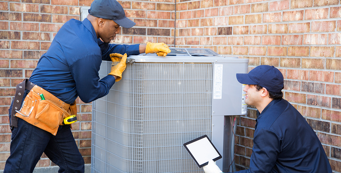 Two men working with an HVAC system