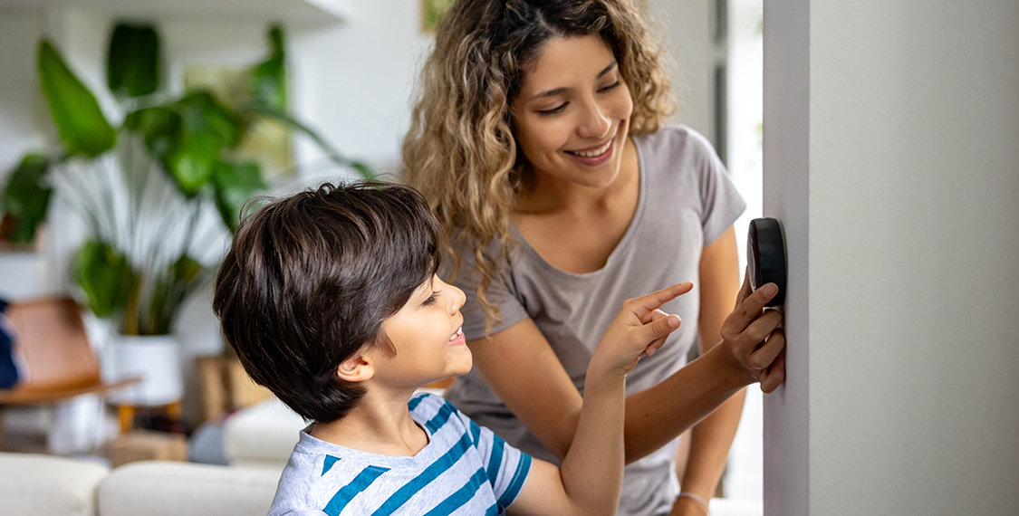 Mother and child adjusting the home thermostat