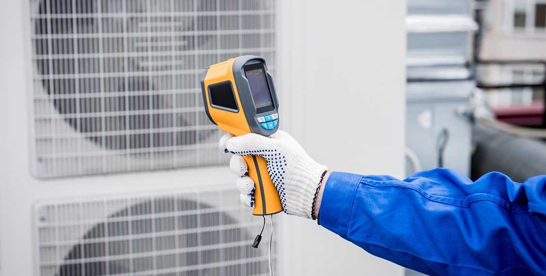 Technician uses a thermal imaging infrared thermometer to check the condensing unit